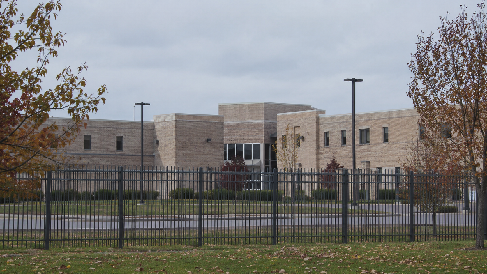 AI-generated editorial imagery of a generic institutional building and security fence; not the actual prison or reported event.